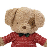 Plush dog toy wearing a red sweater with white patterns and a green bow tie on a white background