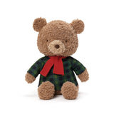 Stuffed teddy bear wearing a plaid shirt and red bow tie on a white background