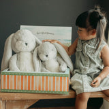 Child interacting with plush toys in a box on a wooden table.