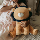 Child holding a plush lion toy on a textured surface