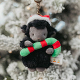 Plush toy sheep keychain with candy cane in front of a Christmas tree