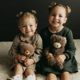 Two young girls holding teddy bears against a dark background