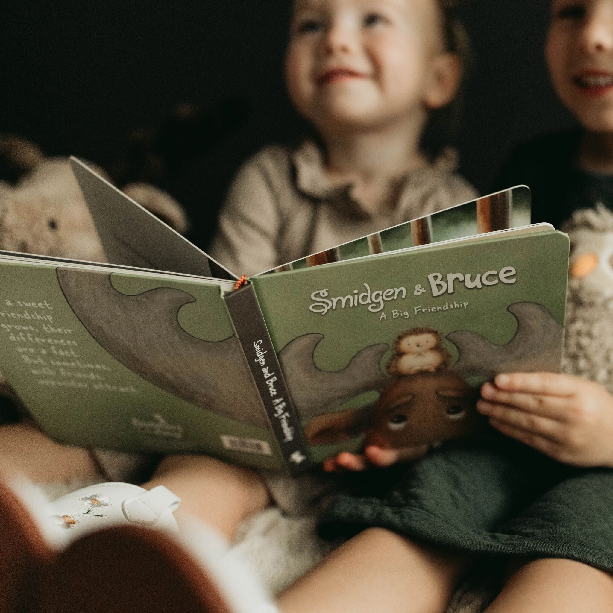 Children reading a book titled 'Smidgen & Bruce' about a big friendship.