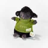Plush toy sheep wearing a green sweater with a carrot tag on a white background