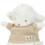 White plush lamb toy wearing a beige sweater with a label on a white background