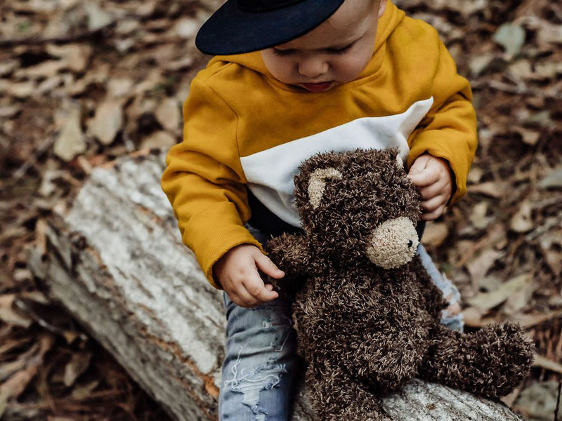 Little kid with stuffed bear in the woods