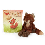 Plush fox toy next to a children's book titled 'Foxy & Blink Flying Lessons' on a white background