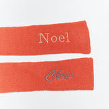 Two red knit scarves with embroidered names on a white background