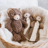 Three teddy bears in a wicker basket on a light background