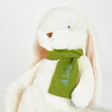 White plush bunny with a green scarf and 'Alex' embroidered on it against a white background