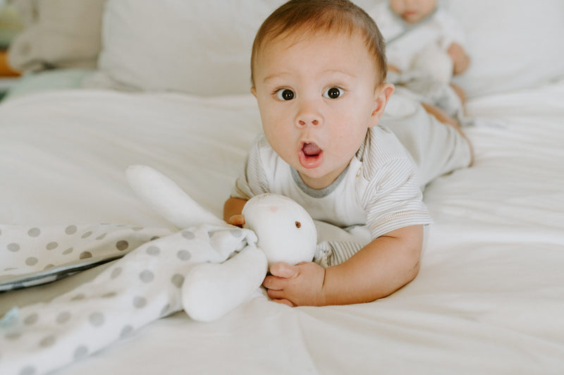 Baby on bed with stuffed animal