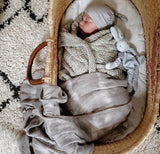 Baby in blanket and bassinet with a blue pacifier holder