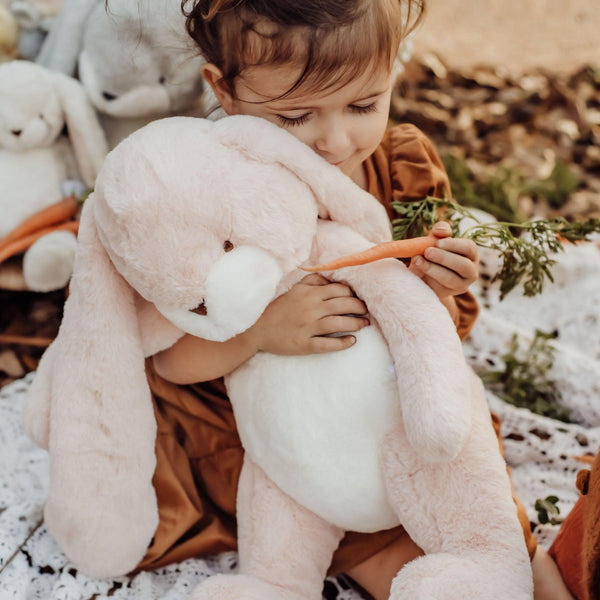 Child holding a pink stuffed animal bunny