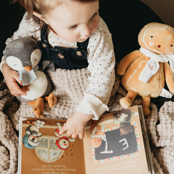 Toddler reading a book holding Holiday stuffed animals