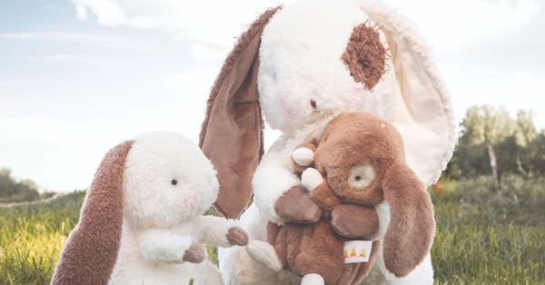 Three bunny stuffed animals in a field