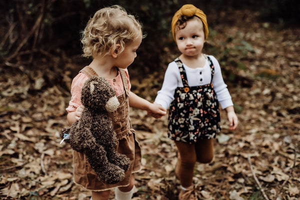 two little girls playing together holding Cubby the bear