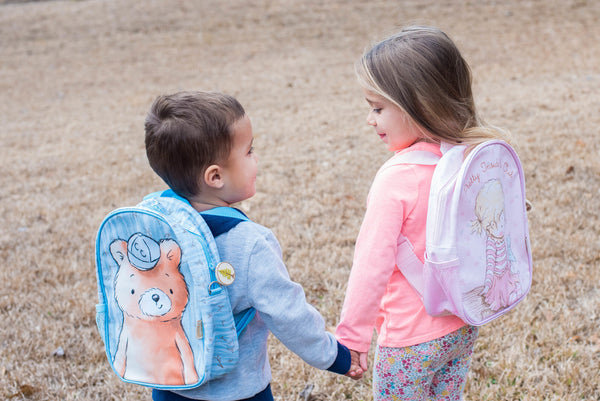 A little boy and girl wearing Bunnies By The Bay Backpacks.   The little boy is wearing the Cubby the Bear backpack.   The little girl is wearing the Pretty Girl backpack
