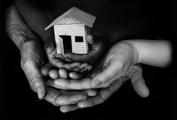 A family's hands holding a replica of a house