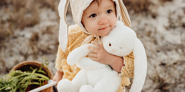 Child sits with her lovey, a stuffed bunny