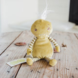 A handmade green plush monster doll with striped arms and legs, sitting on a rustic wooden table.