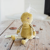 A green plush monster toy with striped arms and legs, a small white tuft on its head, and embroidered facial features, sitting on a rustic wooden tabletop.