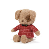 Stuffed dog toy wearing a red sweater with white patterns on a white background