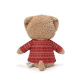 Teddy bear wearing a red sweater with white patterns on a white background