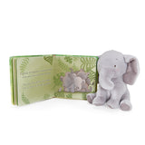 Plush elephant toy next to a children's book with elephant illustrations on a white background