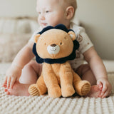 Baby sitting on a bed with a lion-shaped plush toy