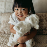 Child holding a white stuffed lamb on a couch