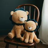 Two lion-shaped stuffed toys with blue manes on a wooden chair.