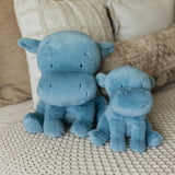 Two blue plush toys resembling hippos on a textured surface with a neutral background