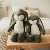 Two plush bunny toys sitting on a wooden surface with a blurred background
