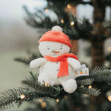 Plush snowman toy with an red hat and scarf on a Christmas tree branch.
