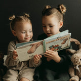 Two young girls reading a book together with a dark background