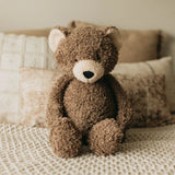 Brown teddy bear sitting on a textured surface with a blurred background