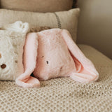 Pink plush toy with ears on a textured surface