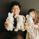 Two children holding three stuffed animals against a dark background