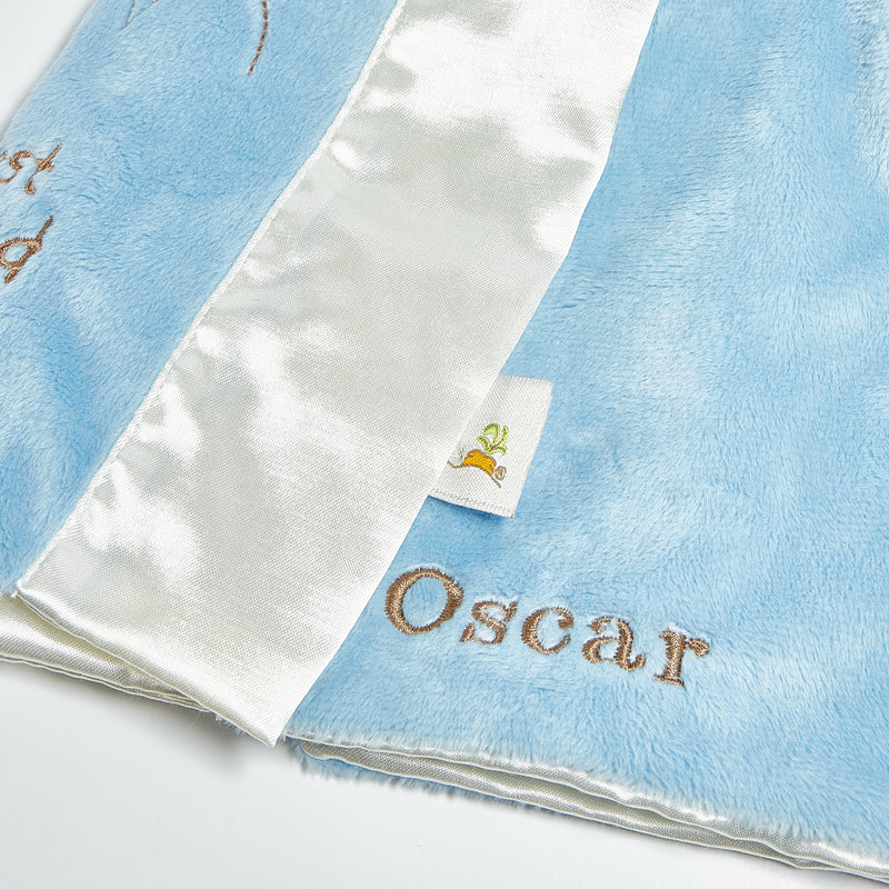 close up shot of Buddy blanket with 'Oscar' custom embroidery on a light blue background