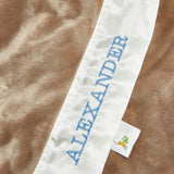 Close up image of "Alexander" embroidered in blue on a white and brown blanket 