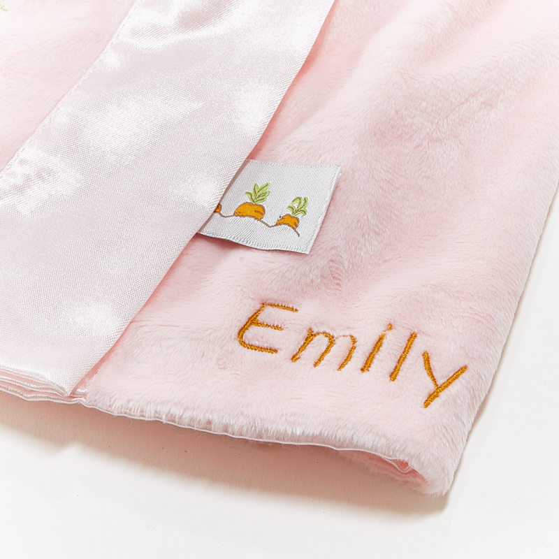 Pink fabric with 'Emily' embroidered on it and a small label with carrot designs.