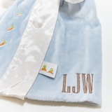 Close up Baby buddy blanket with custom embroidered initials "LJW" and carrot patterns on a light blue background