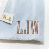 Light blue lovie with brown embroidered initials and a tag on a white background