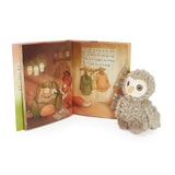 Open book with illustrated fox and owl scene next to a plush owl toy on a white background