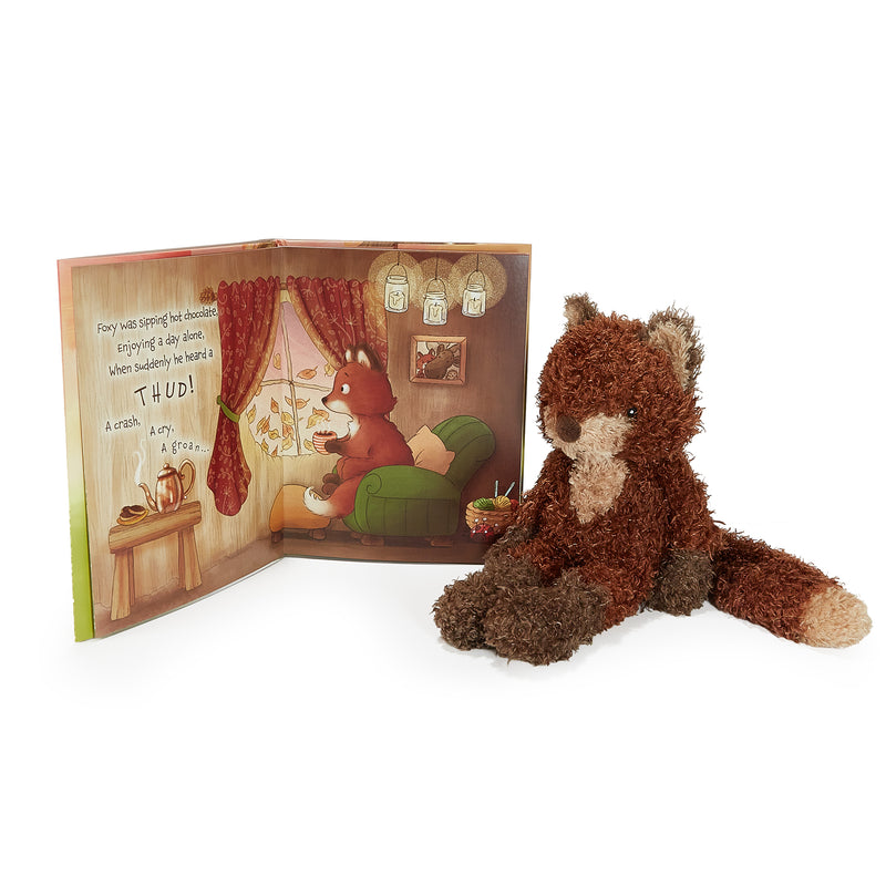 Stuffed fox toy next to an open book with a fox illustration on a white background