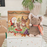 Plush mouse toy with a striped scarf next to a children's book titled 'The Littlest Holiday Helper' on a decorative surface.