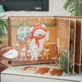Children's book with Christmas-themed illustrations of a polar bear, reindeer, snowman, and gingerbread man on a white surface.