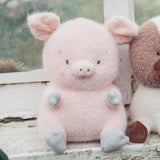 Pink plush pig toy sitting on a wooden surface with a blurred natural background