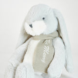 Plush bunny toy with a grey scarf on a light gray background