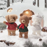 Three teddy bears in winter clothing standing in the snow with a small wooden cabin in the background.